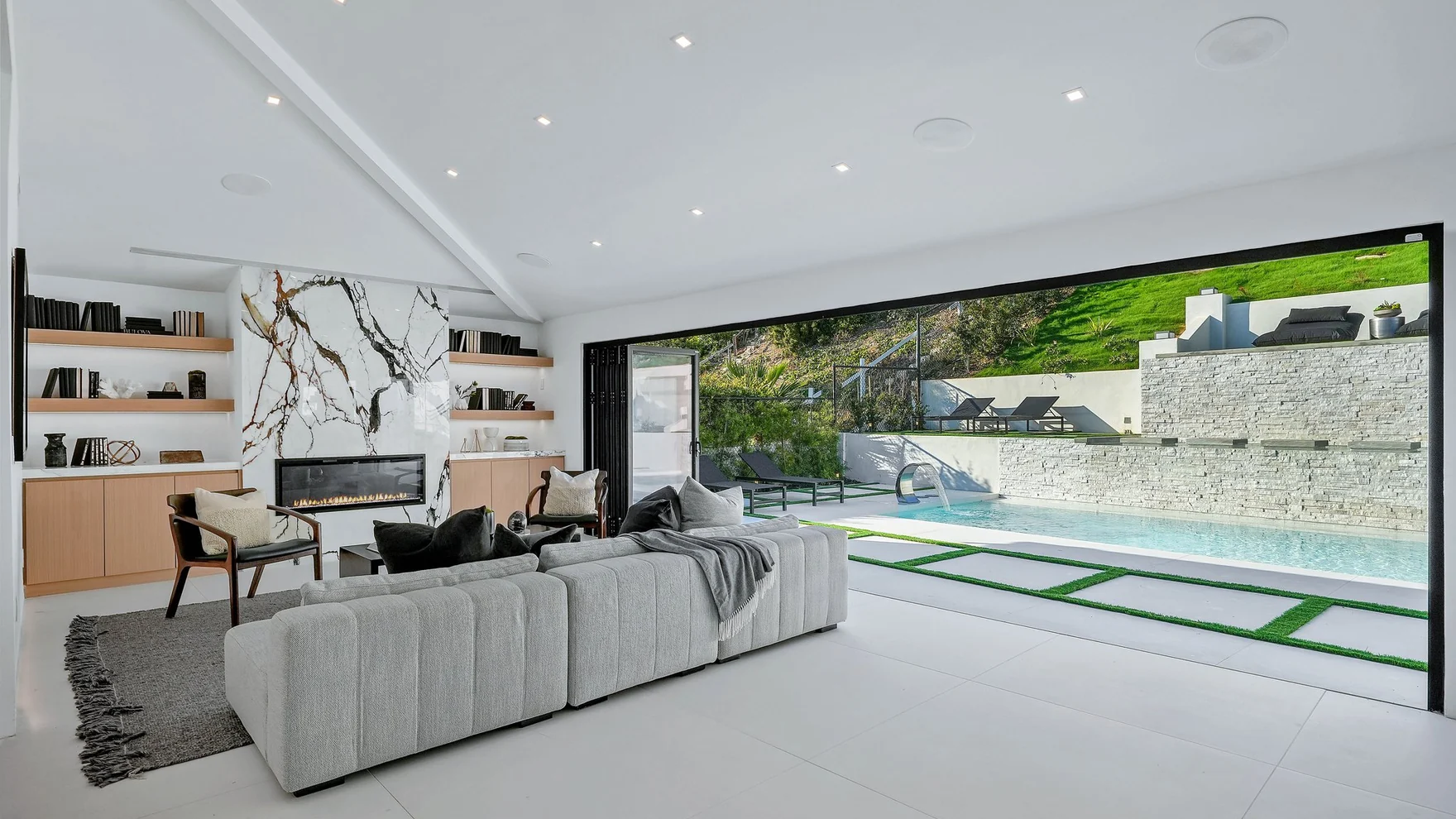 Sitting area with the glazing pocketed away entirely, so the floor carries out to the deck without a threshold