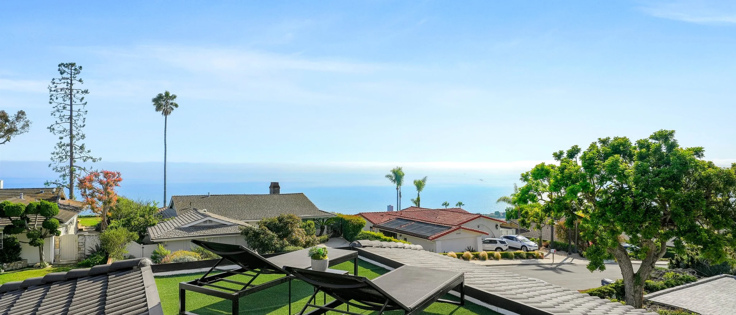 Lawn and terrace at the rebuilt house looking out past palms to the ocean